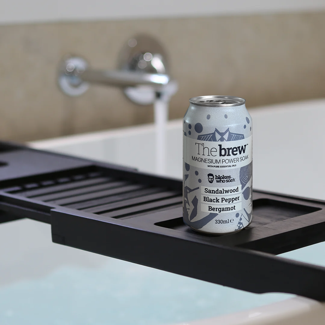Can of The brew™ on a black bath caddy over a hot bath with running tap.